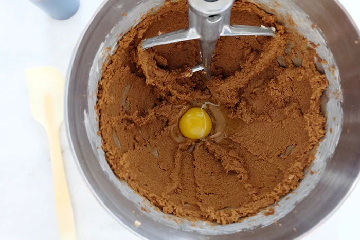 adding egg to creamed butter and dark brown sugar in mixer