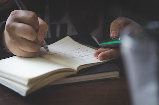 Close up of a hand writing notes with a pen in a book