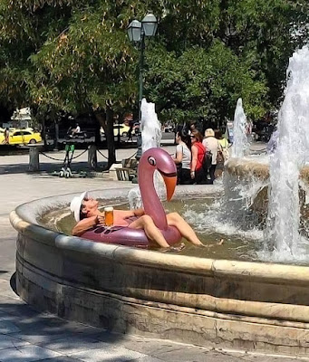 Sommerbilder - Mann relaxt mit Bier und Luftmatratze im Stadtbrunnen