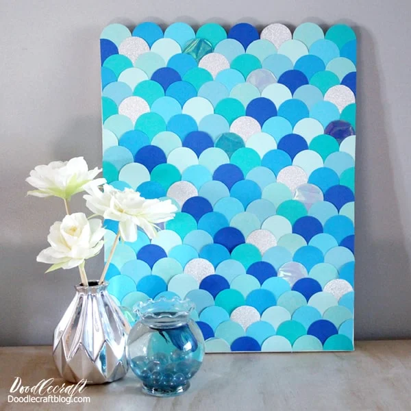 How to make Mermaid fish scales wall art with paper circles in various shades of blue. The different shades of blues, the glitter paper and the iridescent shimmer make this mermaid scale wall art the perfect home decor or party decoration.