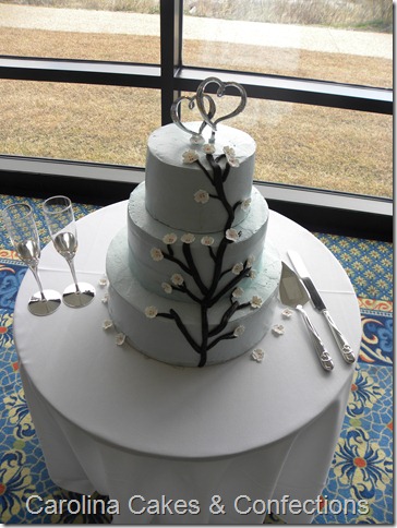 Light blue round wedding cake with white cherry blossoms decorating the 