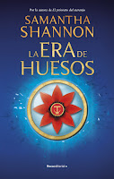 Portada de La era de huesos, de Samantha Shannon, con fondo azul y en el medio un circulo dorado con una flor de 8 petalos rojos y un simbolo.
