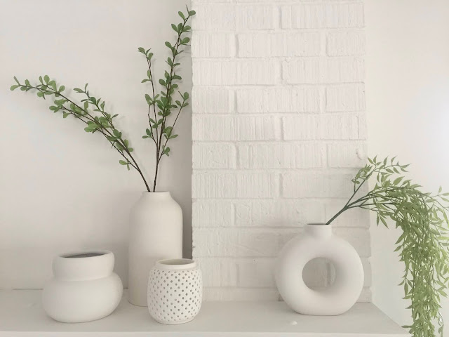 collection of modern white sculptural vases on fireplace mantle