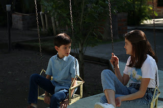 Youth and adult seated on swings talking to each other