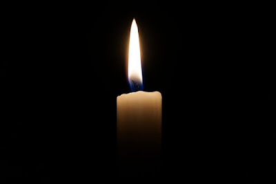 A single lit candle in the dark