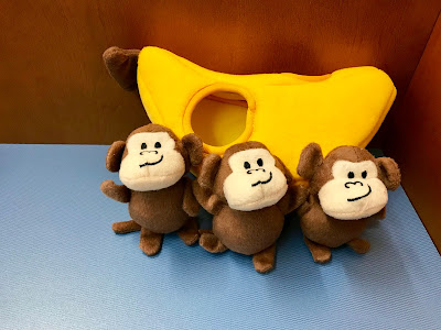 Three small monkeys with a large yellow banana