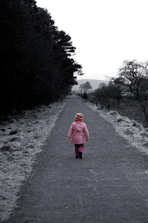 Photo of a small girl walking down a deserted road alone