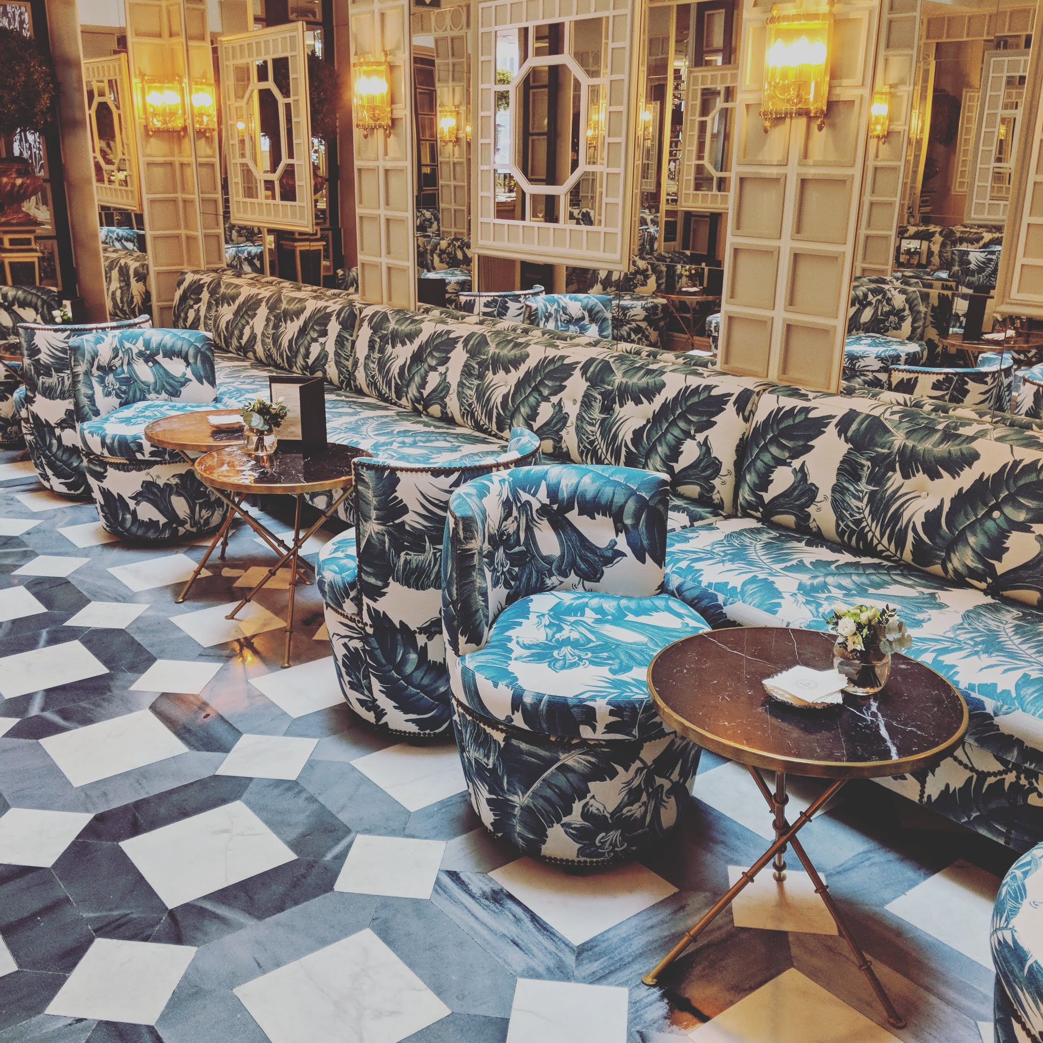 ornate mirror room with palm printed fabric covering arm chairs at the heritage madrid hotel