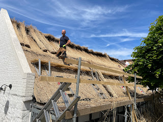 Roofers replacing a thatched roof