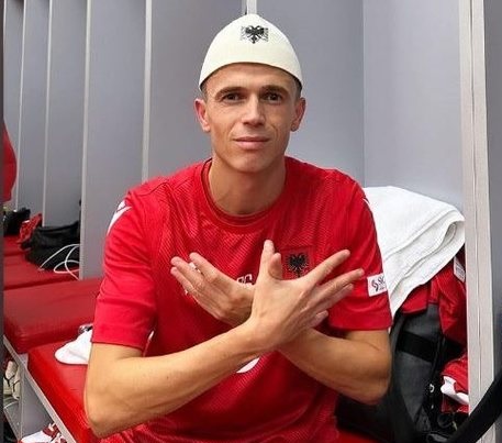 Jasir Asani with a "plis" on his head, wearing the Albanian national jersey, performing the double-headed eagle symbol with his hands