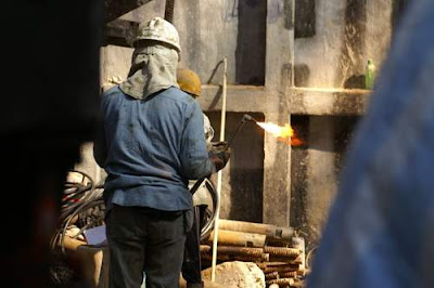 Image of a Hong Kong construction worker having just lit an oxy-acetylene torch.