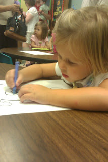 A little girl coloring at a table with crayons