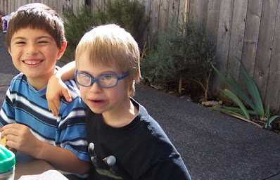 Lisa's young son and his other friend, sitting at a picnic table, and smiling