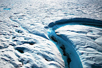 Meltwater pools form on Greenland's surface as temperatures rise and feed into rivers that funnel water toward the ocean. New research shows ice slabs are now forming in areas where water used to sink into the snow layer, increasing runoff. (Credit: Dave Walsh/VW Pics/Universal Images Group via Getty Images) Click to Enlarge.