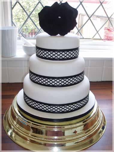 Three tier wedding cake with black ribbon and decorative silk black flower 