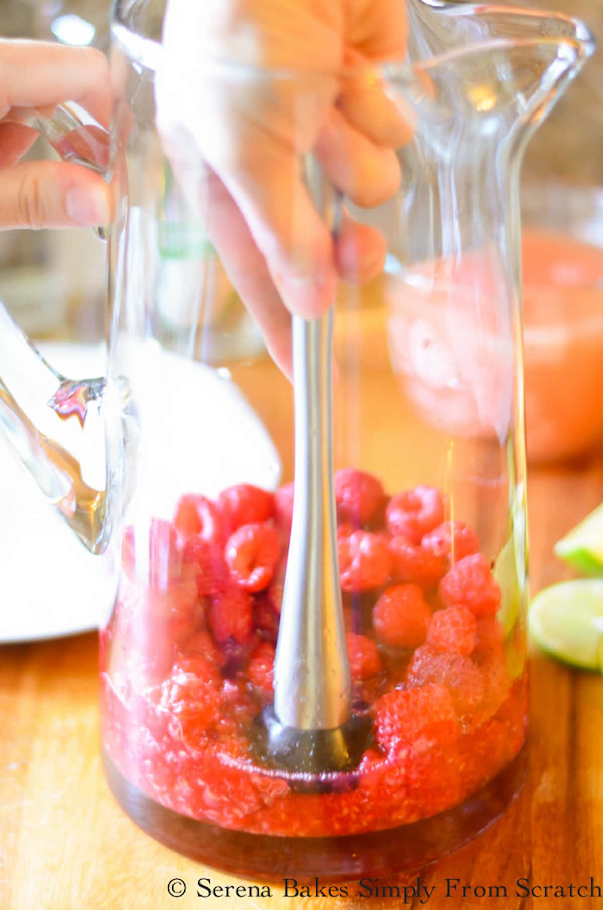 Macerating Raspberries with Agave Nectar in a glass pitcher using a stainless steel macerator.