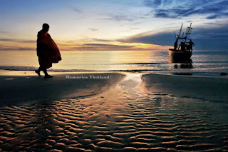An elderly monk walking along the low sea water on the beach in Hua Hin