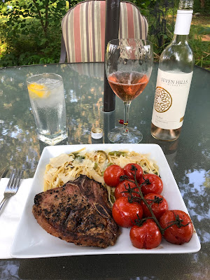 Grilled veal loin chop with blistered Campari tomatoes and linguine tossed with asparagus and garlic scapes sautéed in olive oil and topped with shaved parmesan