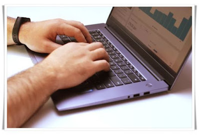 a guy is typing a laptop keyboard