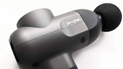 The Bob and Brad C2 Massage Gun laying on it's side with the round head attachment.