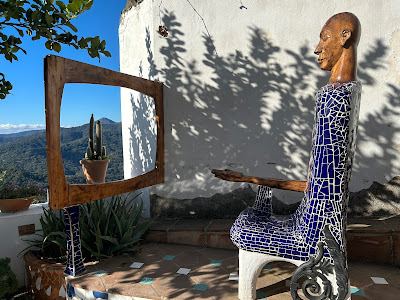 Artwork of a sculture watching a fake TV frame that is just a view of the mountains