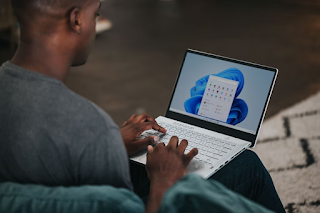 A man looking at a Windows 11 vomputer with a flower looking background.