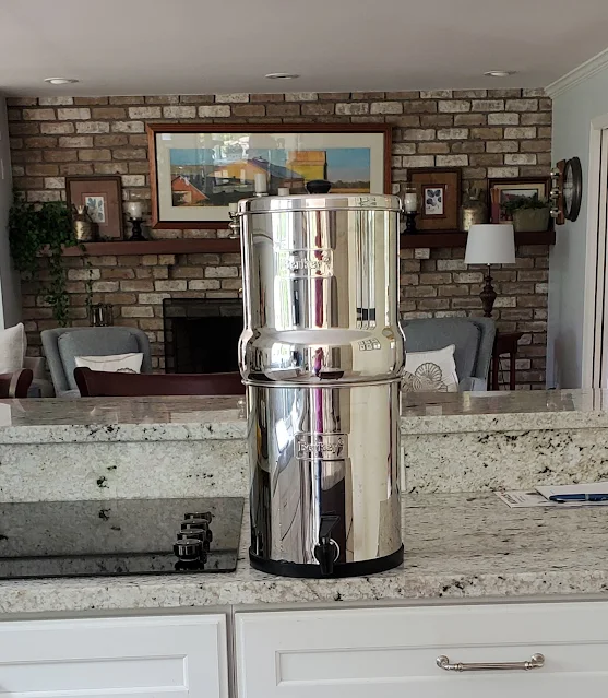 The Big Berkey water filter on a counter in a kitchen beside the stove.