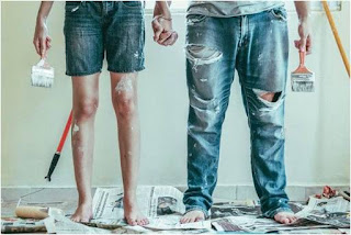 Couple holding hands and brushes after repainting walls