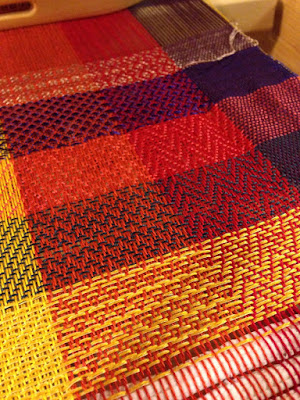 A bright color gamp, with warp running in panels from left to right of white, yellow, orange, red, and purple, and weft blocks in a variety of colors. Every new weft color also shows a new set of twill patterns.