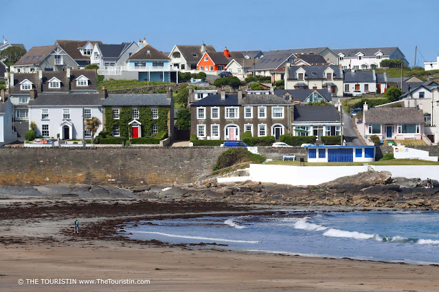 A single woman walks on the beach of a small village.