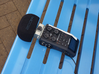 A portable recording device on a bright blue bench, in a railway station.