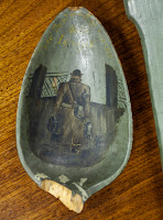 The broken-off bowl of a spoon featuring a painting of a man from behind.