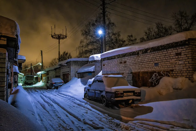 Машина занесенная снегом в проезде между гаражами