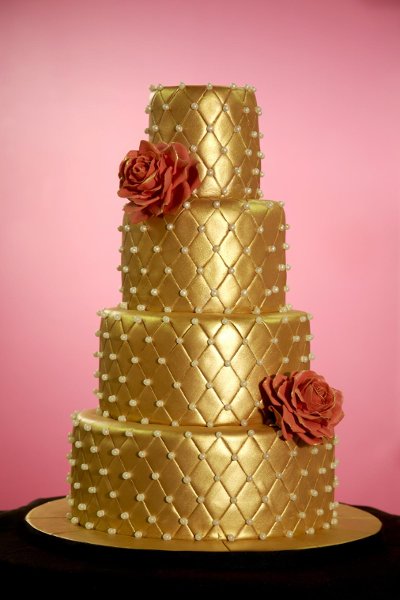 Four tier quilted gold wedding cake with two red roses Source A white sugar