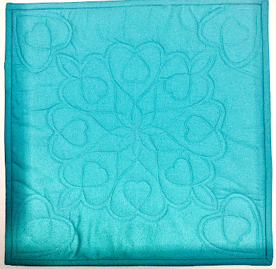 A stencil design of hearts on a blue quilt square