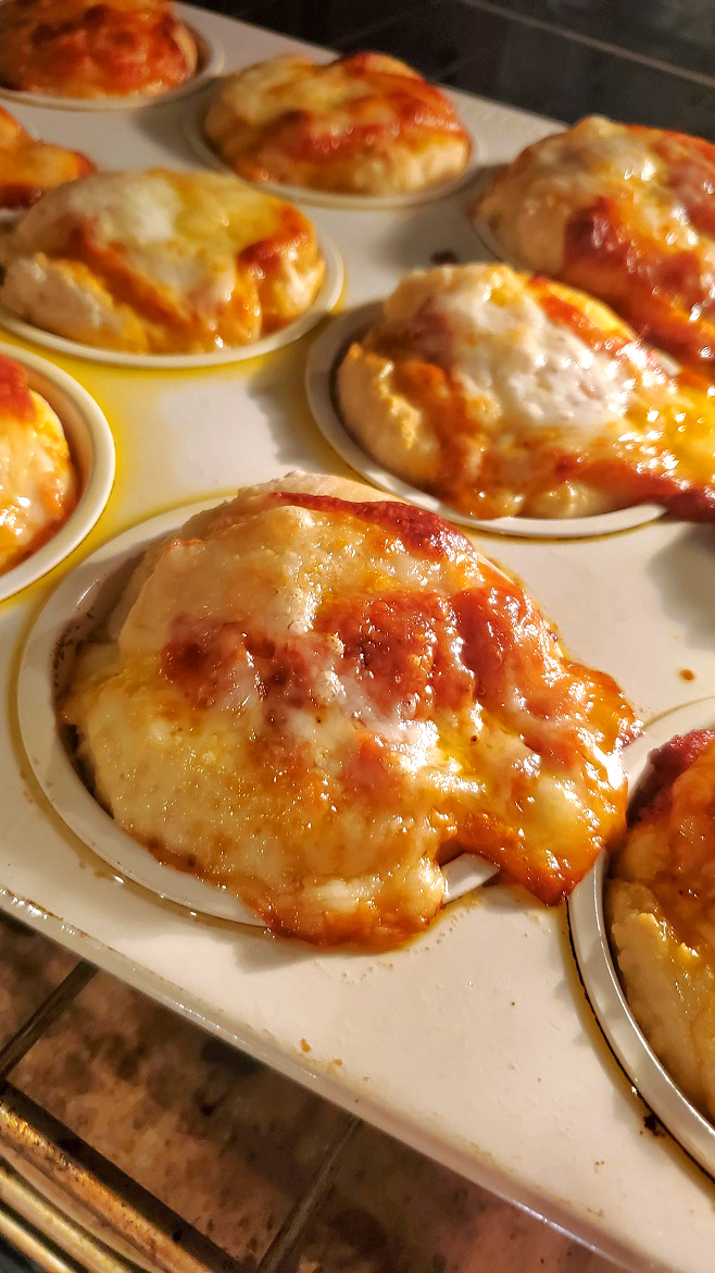 pizza baked in a muffin tin with cheese, sauce and mozzarella