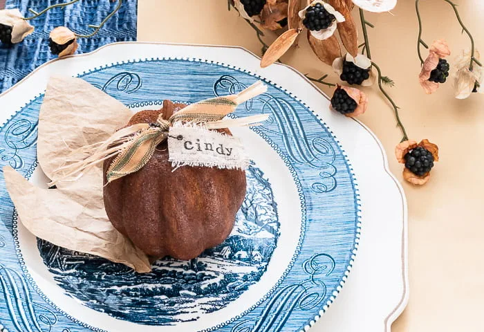 primitive brown pumpkin with name tag on blue and white vintage plate