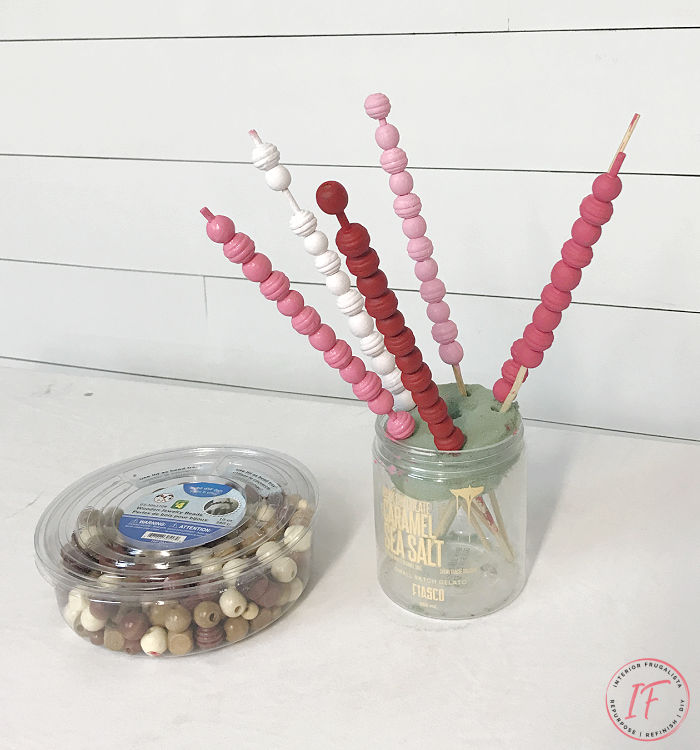 A budget-friendly DIY wooden bead garland painted a pretty gradient pink ombre for Valentine's Day made with a string of dollar store wooden beads.