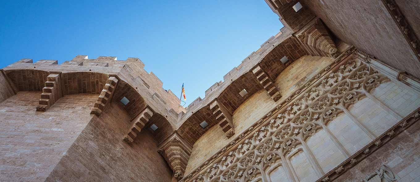 A close-up picture looking up at the blue sky infront of a building in the city of Valencia.