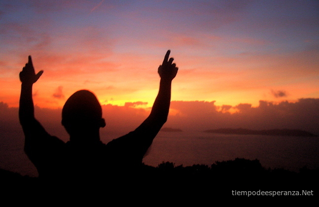 Hombre mirando al cielo levantando sus manos en la atardecer