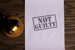 A gavel such as a Judge would use and the words "Not Guilty" stamped on a white piece of paper.