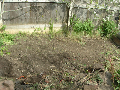 A weeded garden bed next to a fence