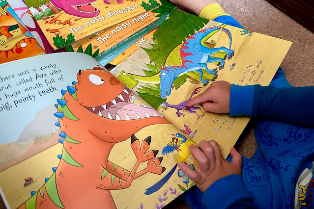A view over a preschoolers shoulder towards a dinosaur picture book