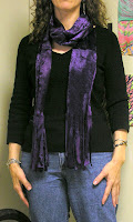 Purple scarf wrapped double around the neck.