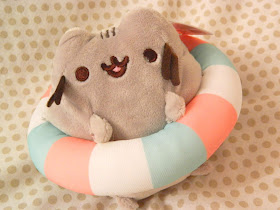 A plushie of Pusheen wearing a rubber ring for swimming