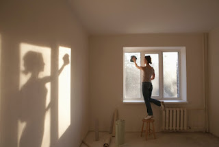 A woman standing on a stool cleaning a window