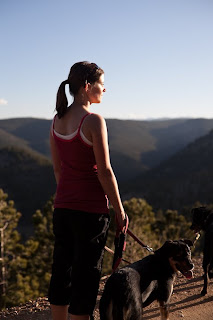 a woman faces the sunset on a walk in the mountains