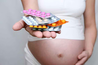 Mujer embarazada con analgésicos en la mano