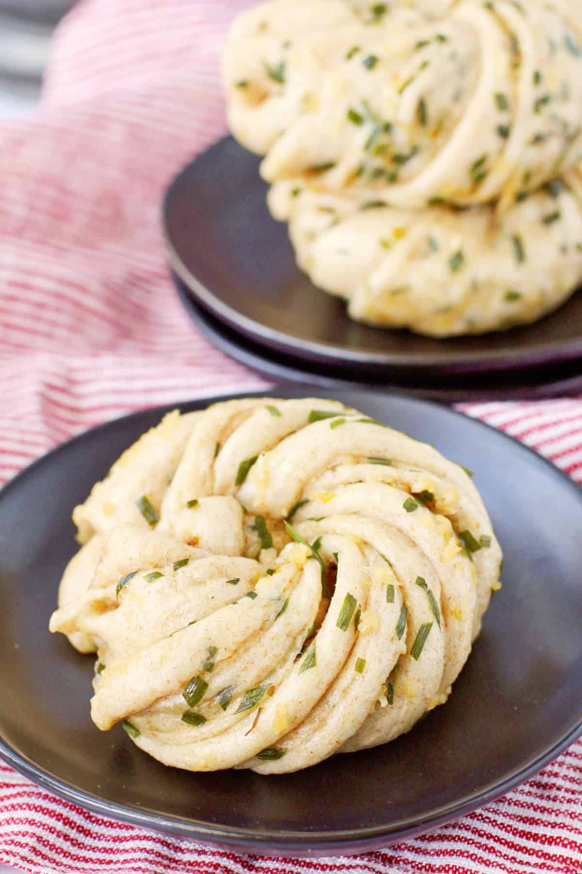 Huā Juǎn with garlic and chives on a black plate.