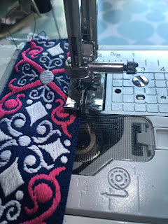 Using a sewing machine to sew the trim to the strap